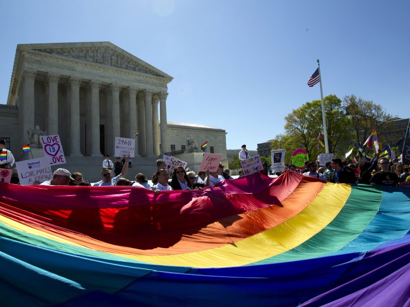 FILE - Demonstrators hold a rainbow pride flag outside the Supreme Court as justices deliberate Obergefell vs. Hodges
